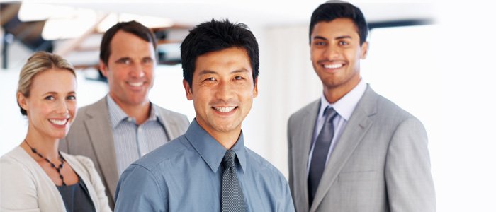 Image of three men and a woman in business attire smiling at camera